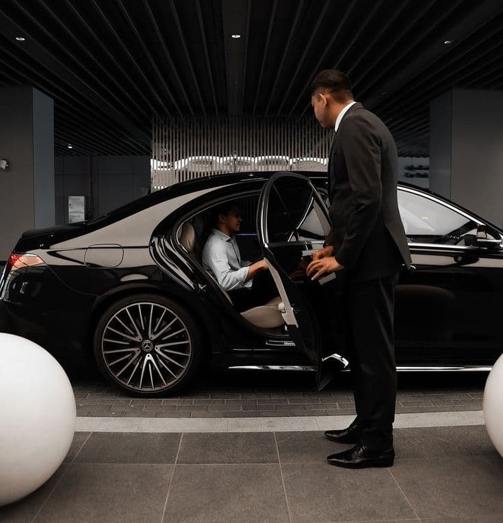 Chauffeur holding open the door of a luxury sedan in Cairo